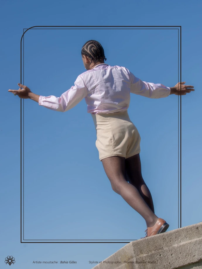 Personne Queer, en chemise rose et mini combi beige à dos nu